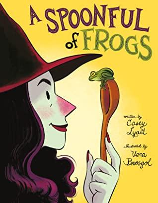 A woman wearing a black witch hat stares a frog sitting on a wooden spoon in her hand.