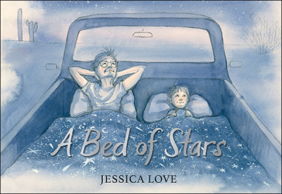 An adult and child lie side by side under a starry blanket in the back of a pickup truck looking up at the sky at night.