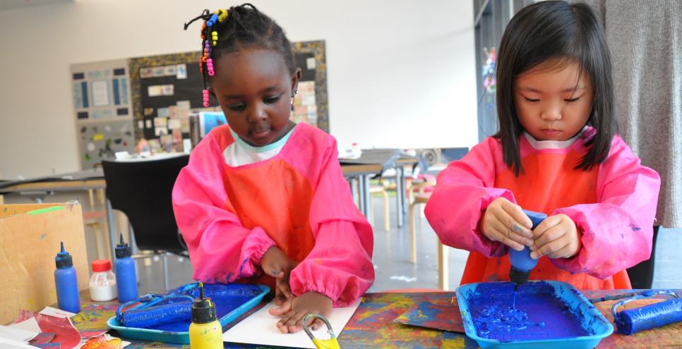 Two young children printmaking with blue paint.