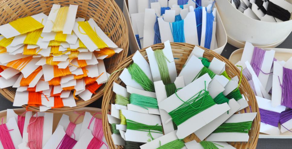 Baskets of colorful embroidery thread on white paper bobbins.