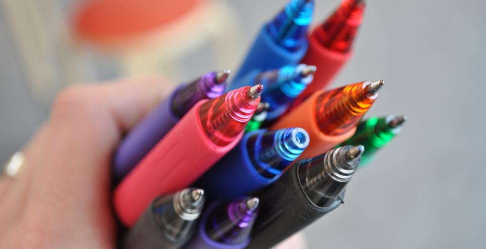 A handful of colorful ballpoint pens.