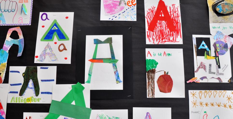 A wall filled with collages inspired by the letter "A" including an alligator, apples, and a hand signing "A."