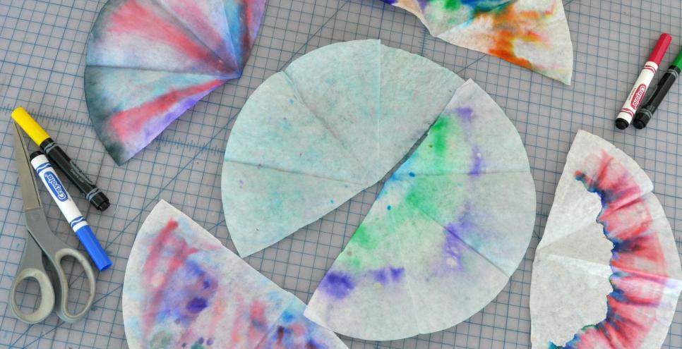 Six coffee filters that have been drawn on with markers then sprayed with, or dipped in, water to make the colors run through the filter.