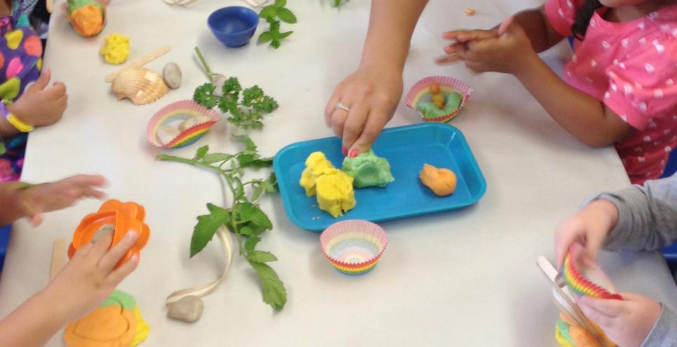 A group of toddlers playing with homemade dough and herbs at a table.