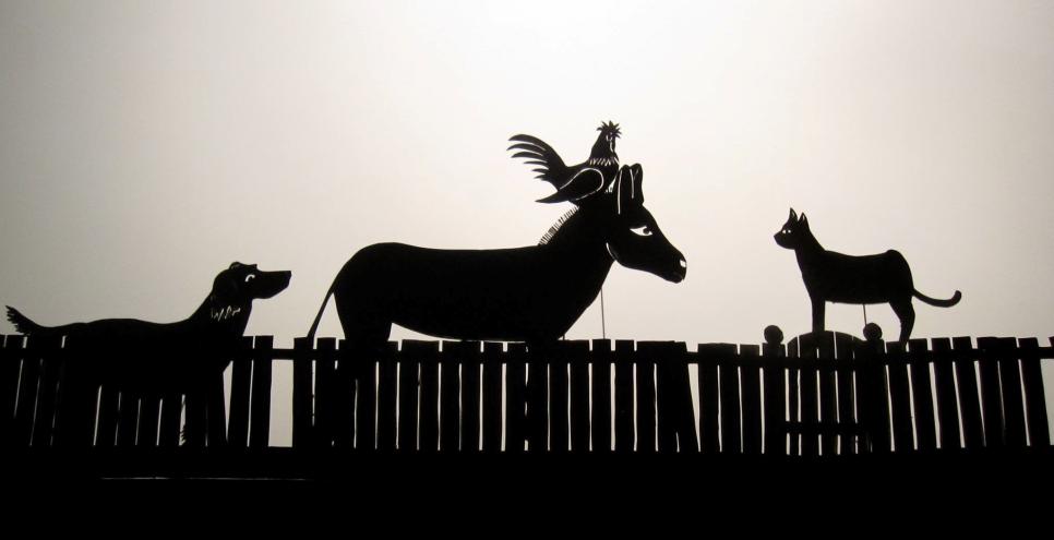 Silhouette animal puppets standing by a fence