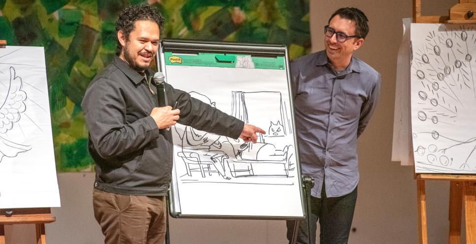 Two artists on stage with drawings on easels.