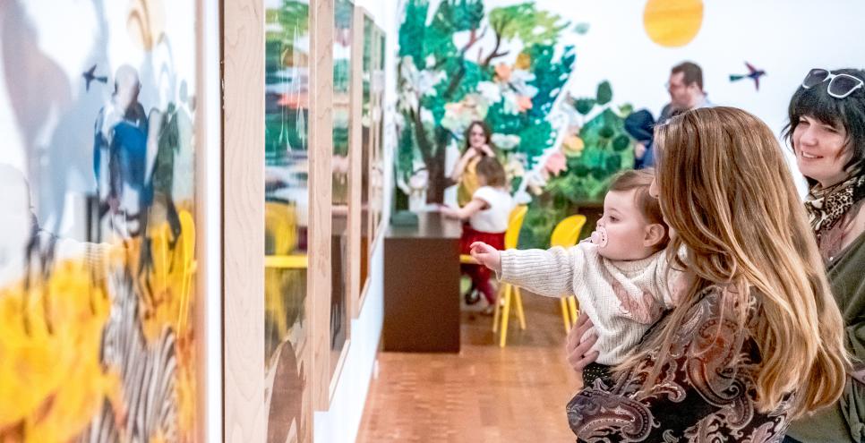 Adults and baby looking at art.