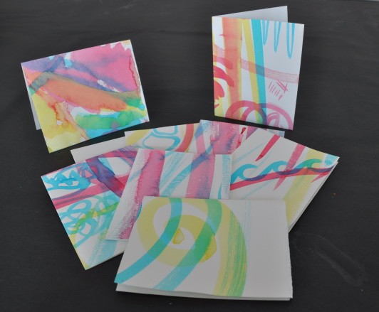 A pile of cards made from the large-scale painting exercise, each one with painted abstract lines and swoops.