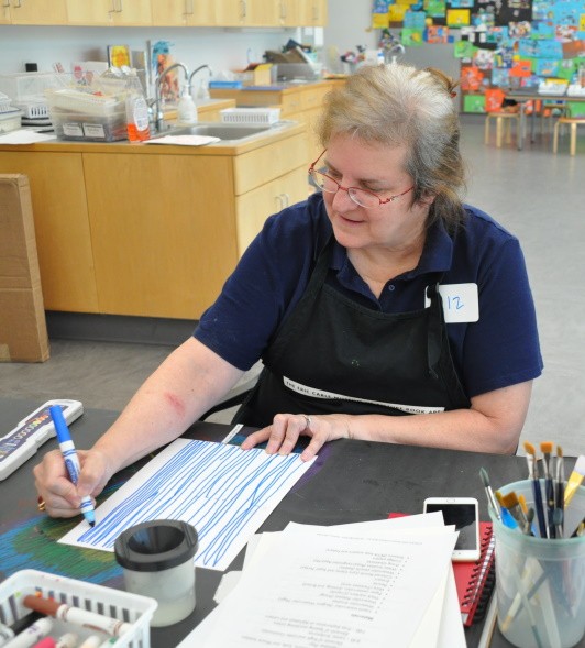 A participant smiles while creating letters that touch the top of the page and go all the way to the bottom.