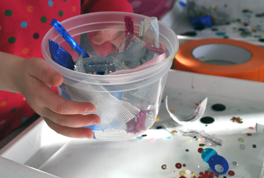 sparkly materials in a deli cup for toddler activity