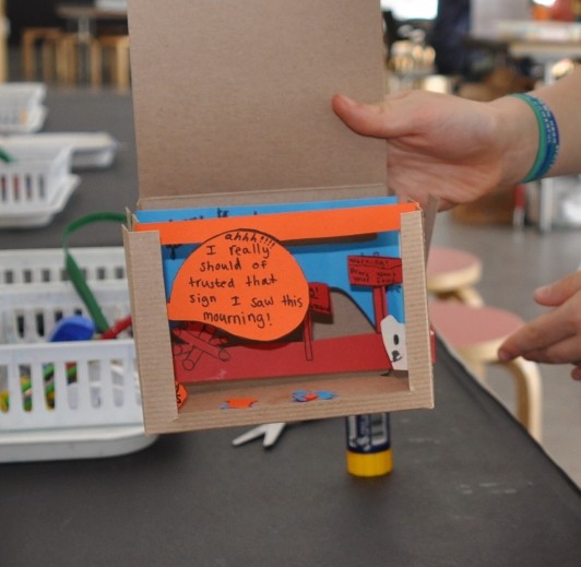 A guest shows their tunnel book that has layered words and drawings.