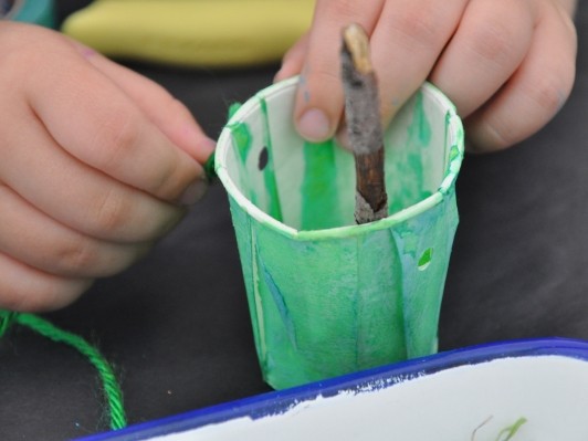 Image of painted found material and small hands tying a string