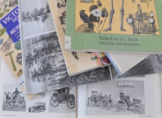 Stack of clip art books with some pages open to cars and trees.