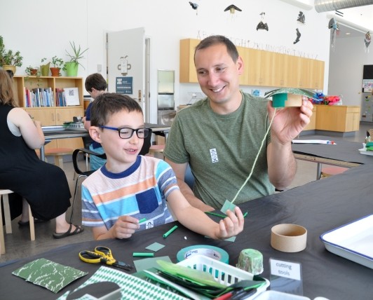 Guests explaining the process of building a mobile and holding materials